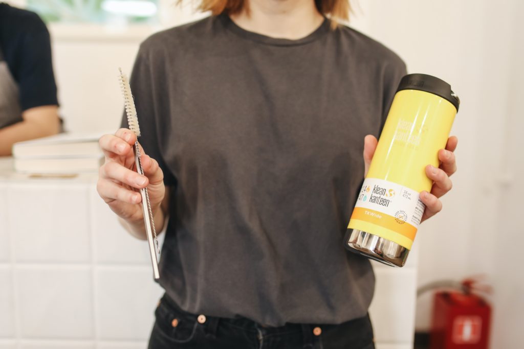 woman holding metal straws and reusable water bottle