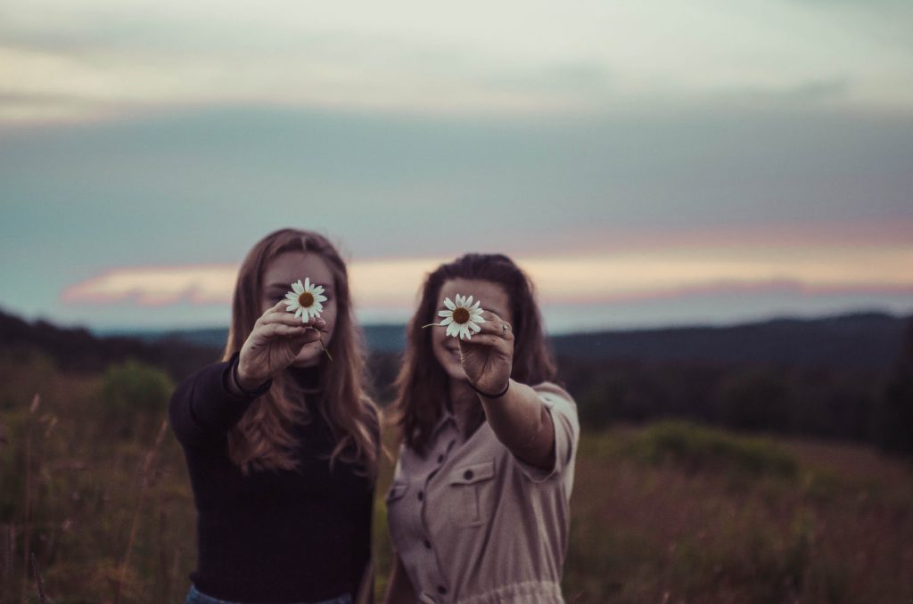 two women holding up daisies