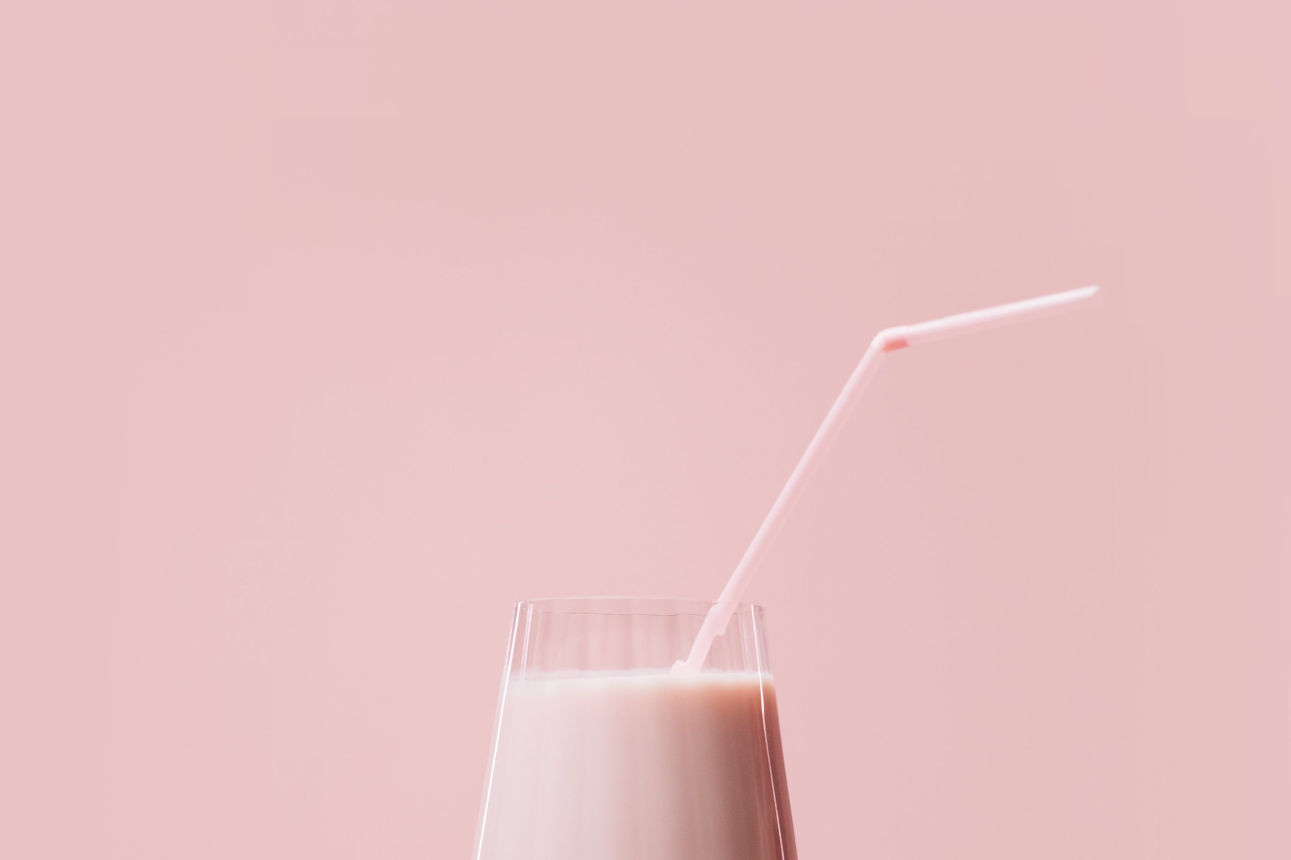 a glass of milk in front of a pink background
